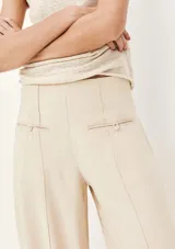 Pantalón de vestir color beige, de corte recto y tiro alto, con bolsillos laterales y traseros.