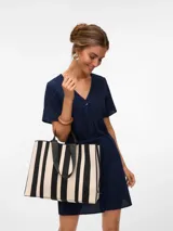 Bolso tipo tote bag con estampado de rayas verticales en blanco y negro, doble asa corta negra y correa larga negra para colgar del hombro.