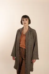 Camisa larga color crema con rayas verticales finas en gris, con botones dorados y bolsillo plaque en la delantera.