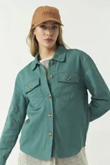 Sobrecamisa color beige con cuello camisero, cierre frontal con botones, dos bolsillos con solapa en el pecho y mangas largas con puños abotonados.
