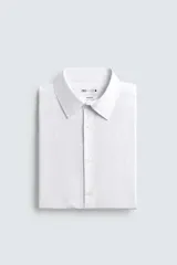 Camisa blanca de corte regular fit, con cuello italiano, manga larga con puños abotonados y cierre frontal con botones.