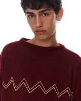 Sweater color borgoña con bordado de líneas en zigzag color dorado en el pecho. Tejido de lana, algodón y viscosa, con terminaciones de cuello y puños a mano.