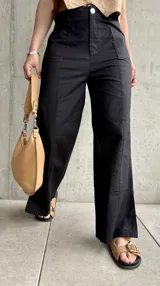 Pantalón negro de lino, de corte recto, con pinzas en la cintura y aberturas laterales en el ruedo.