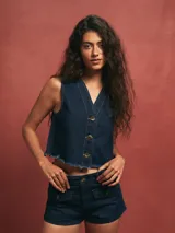 Chaleco azul oscuro de denim con botones y terminación desflecada.