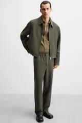 Pantalón largo color verde oscuro, de corte recto y tiro medio. Confeccionado en tejido con viscosa, con cintura elástica, bolsillos laterales y trasero de vivo. Cierre frontal con cremallera y botón.