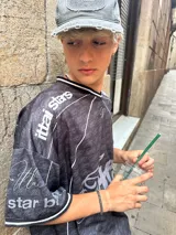 Camiseta negra con estampado de logos en gris y blanco, cuello redondo y mangas cortas. Diseño con ribetes blancos en cuello y mangas.