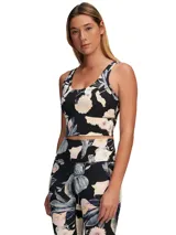 Musculosa deportiva corta con estampado floral en tonos pastel sobre fondo negro.