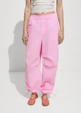 Pantalón parachute rosa con cintura elástica, dos bolsillos laterales y bajo ajustable con goma elástica.