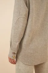 Camisa estilo leñador color beige con textura de espiga, de manga larga con puños abotonados, cuello clásico, cierre frontal con botones y dos bolsillos de parche con solapa abotonada en el pecho.