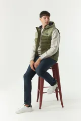 Chaleco inflable verde oliva con capucha ajustable, cierre frontal y bolsillos laterales con cierre.