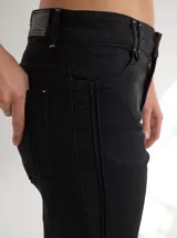 Pantalón negro de gabardina con alforzas verticales en los laterales y aberturas en los tobillos.