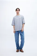 Remera verde con rayas horizontales azul marino, corte boxy y estampado con el número 1956 en el pecho.