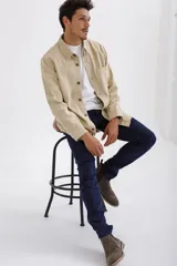 Campera color beige con cuello camisero, cierre frontal con botones a tono, manga larga con puños abotonados y bolsillo de parche en el pecho.