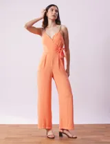Enterito de crepe color naranja, marca Luxology. Escote en V cruzado, cintura elastizada con lazo de ajuste, espalda en punto smock y breteles de cadena.