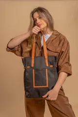 Cartera tipo tote bag color negro, con doble asa de mano y correa bandolera ajustable. Presenta un bolsillo rectangular en el frente.