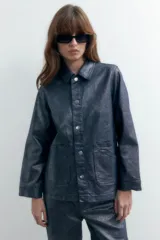 Sobrecamisa de denim metalizado color azul con cuello clásico, cierre frontal con botones, bolsillos de parche en el pecho y mangas largas.