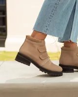 Botín corto de cuero color visón (beige/topo), con cierre de tres tiras de velcro en el empeine. Posee cuello acolchado de gamuza y suela de goma negra con relieve tractor.