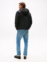 Campera rompeviento de poliéster reciclado con capucha ajustable. Presenta un diseño liso en color negro, cierre frontal completo, puños elásticos y el logo de Tommy Hilfiger engomado en la manga.