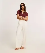 Blusa blanca acanalada de rib con cuello polo negro contrastante y mangas cortas.