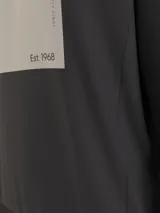 Buzo negro de corte clásico con cuello redondo y mangas largas. Presenta un logo cuadrado en la parte delantera con el nombre de la marca y el año de fundación.