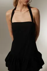 Vestido mini negro sin mangas de algodón, con cuello recto, corte ajustado y falda con volados.