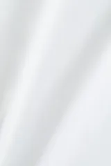 Remera blanca de corte holgado, con cuello redondo y mangas cortas. Confeccionada en tejido de punto suave.