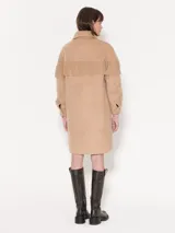 Tapado de paño color beige con flecos en la parte superior y broches al tono. Forrería estampada con print de monas. Diseño de la colaboración entre Jazmin Chebar y Edgardo Giménez.