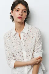 Camisa amarilla de cuello solapa y manga larga acabada en puño. Detalle de bordados perforados a tono. Cierre frontal con botones ocultos por solapa.