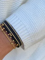 Pulsera tejida con cuentas Miyuki originales en tonos negro y dorado, con terminación de dos cuentas en acero dorado.
