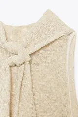 Top color crema de tejido de punto con cuello halter fluido y hombros descubiertos. Detalle de hilo metalizado.