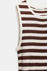 Vestido largo de cuello redondo y manga sisa, con tejido de textura. La parte superior presenta rayas horizontales marrones y blancas, mientras que la parte inferior tiene un diseño plisado con rayas verticales marrones y blancas.