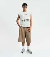 Musculosa negra de algodón con corte recto y hombros ligeramente ampliados (boxy fit). Presenta estampado frontal en blanco con el texto "URBAN SCENE TRENDS", "NEW YORK" y "Manhattan 1974".