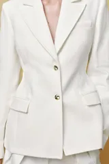 Blazer color blanco confeccionado en algodón, con cuello solapa de muescas y manga larga. Tiene bolsillos con solapa en delantero, forro interior a tono y cierre frontal con botones metálicos en relieve.