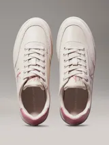 Zapatillas bajas Calvin Klein Jeans color crema con logo CK rosado en el lateral y detalle rosado en el talón.