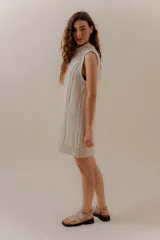 Vestido corto tejido color beige, sin mangas y con cuello redondo.