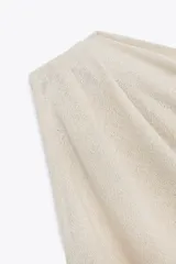 Top blanco de tejido de punto con escote asimétrico y un solo tirante.