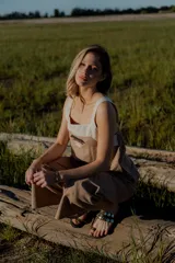 Conjunto de top y pantalón color beige. El top es de breteles anchos, con detalle en dos colores y un bordado en su delantera. El pantalón es liso, de corte recto ancho con bolsillos a los costados y cintura con botones y elástico.