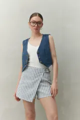 Short pollera con estampado a rayas verticales azules y blancas, con hebilla metálica lateral y corte asimétrico.