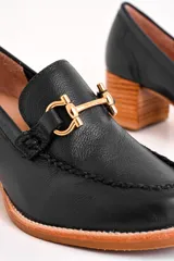 Mocasín de cuero color azul marino con aplique metálico dorado y taco de madera.