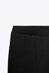 Pantalón negro de tiro alto confeccionado en tejido de punto elástico y flexible con trama compacta, mullida y opaca. Bajo acampanado.