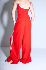 Pantalón Adidas Parachute negro de corte holgado con las tres rayas blancas a los costados.