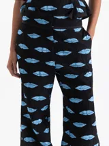 Pantalón tipo babucha negro con estampado de labios azules, confeccionado en jacquard. Cuenta con cierre, doble gancho pantalonero y botón interno, puño elástico en el ruedo, bolsillos laterales y bolsillos ojal traseros.