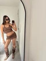 Conjunto de top y minifalda marrón con textura de encaje. El top es de corte halter y la falda es ajustada con cordones laterales.