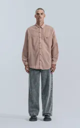 Camisa manga larga rosa con bolsillo con ojal y botón en delantero, de calce oversize confeccionada en textil plano fresco y liviano.