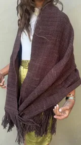 Ruana artesanal tejida en telar con lana merino de alta calidad, color marrón chocolate obtenido con teñido natural. Presenta un tejido grueso y textura visible, con flecos largos en el borde inferior.