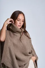 Poncho polerón tejido color marrón claro, con cuello alto y diseño holgado.