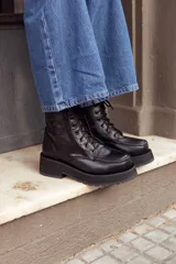 Botas de cuero negras con cordones, cierre lateral con cremallera y suela track de goma.