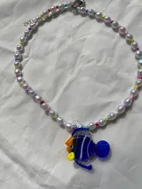 Collar corto de perlas blancas con mostacillas de colores y dije de vidrio con forma de pez azul, amarillo y naranja.