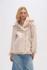Campera color beige de eco-cuero con cuello y solapa de piel sintética, cierre frontal con cremallera, bolsillos laterales con cremallera y cinturón con hebilla en los puños.