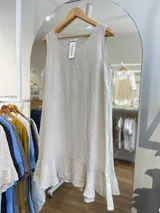 Vestido corto blanco, sin mangas, de corte suelto y con un volante en el ruedo.